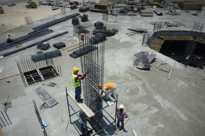 Construction workers assembling steel reinforcement on a large building site.