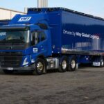 A visy logistics freight truck is parked next to a warehouse.