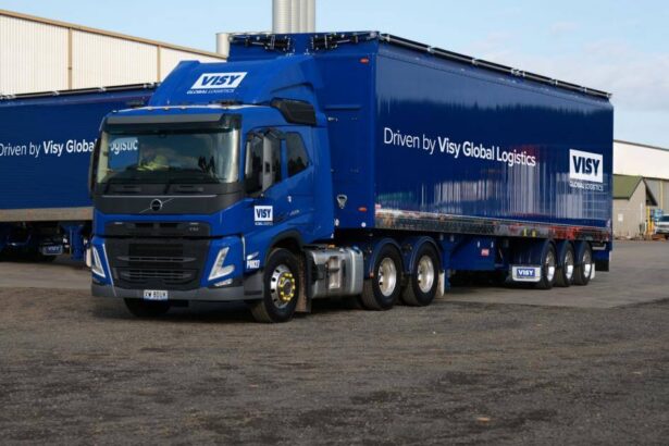 A visy logistics freight truck is parked next to a warehouse.
