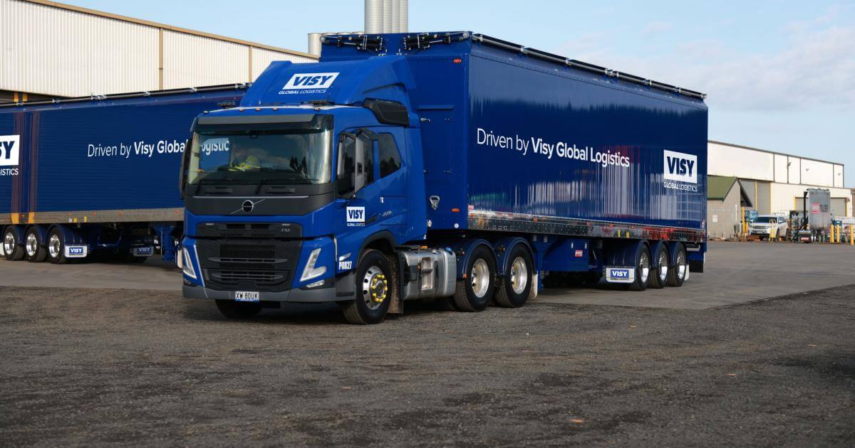 A visy logistics freight truck is parked next to a warehouse.
